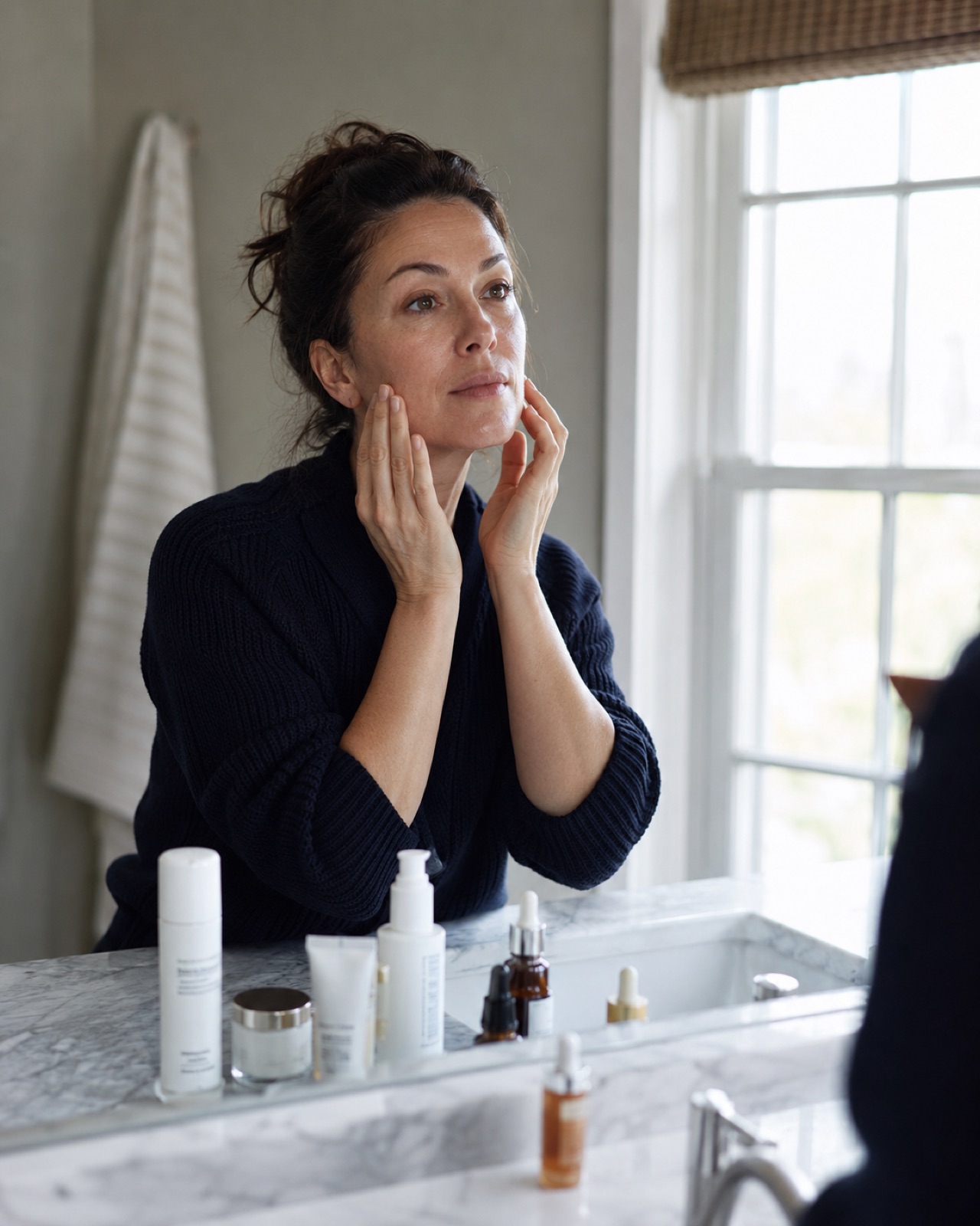 A woman checking her skin in the bathroom mirror