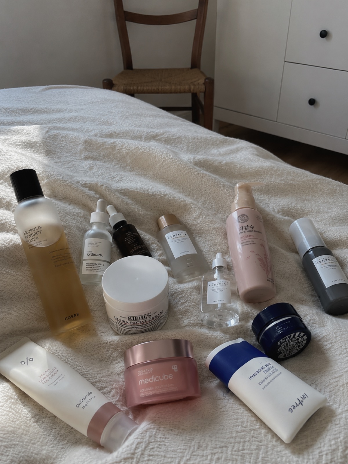An assortment of skincare products laid out on a bed