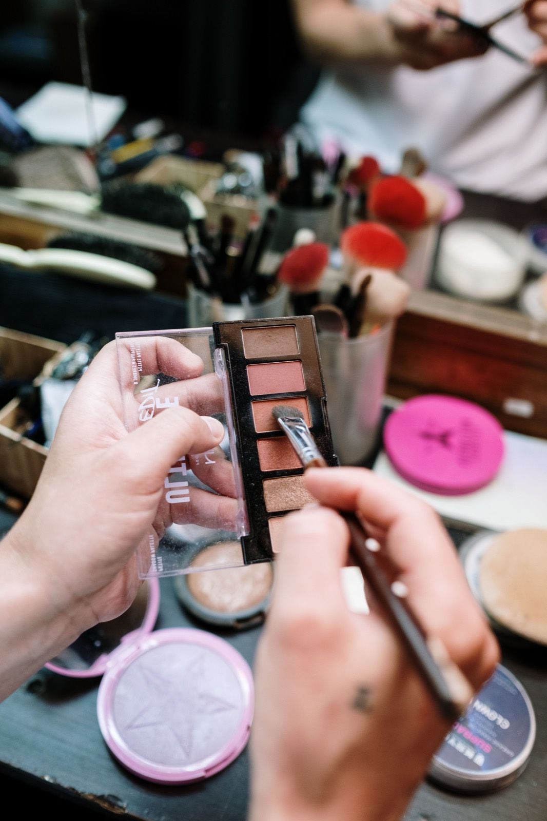 A makeup palette being used with a brush, almost hitting the pan